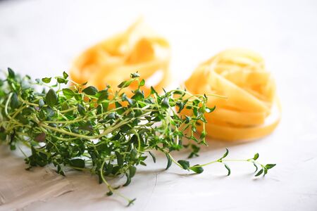 Italian traditional pasta tagliatelle with dried tomatoes and thyme on a light background.の写真素材