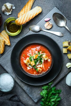Traditional spanish cold tomato soup gazpacho in a bowl over black slate, stone or concrete background.Top view with copy space. の写真素材