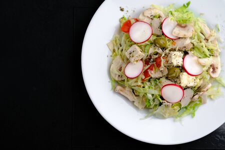 Salad of young cabbage, tomatoes, radishes, greens with olives, chicken and feta cheese. Top view copy space.の写真素材
