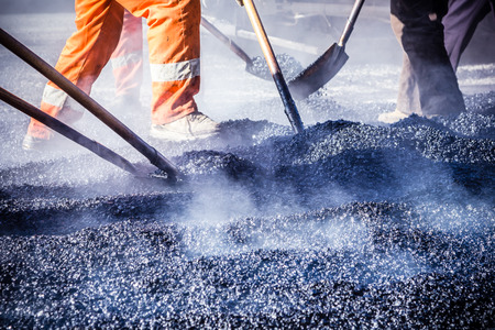 Workers making asphalt with shovels at road constructioの写真素材