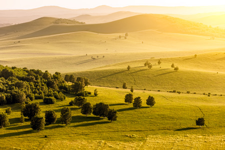 Mountains and grassland at sunsetの写真素材