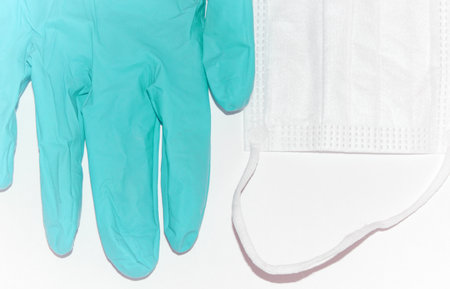 Light blue or turquoise medical latex glove and protective mask on a white background. Disposable rubber medical gloves and mask. Personal protective equipment. Therapeutic agentsの写真素材