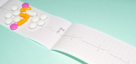 Medications in the form of tablets for oral administration against the background of an electrocardiogram. The heartbeat is shown on the graph, blue backgroundの写真素材