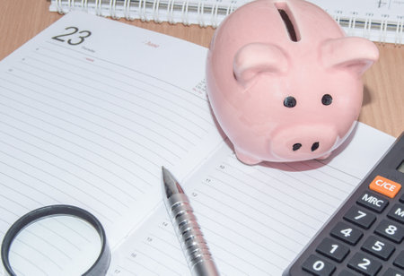 Piggy Bank, calculator, magnifying glass and pen on the organizer for business planning. Business concept of saving financesの写真素材