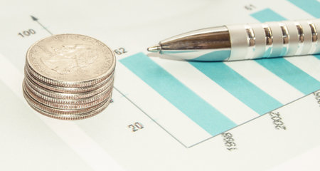 The concept of financial analysis, pen and stack of coins on the paper work, schedule and chartの写真素材
