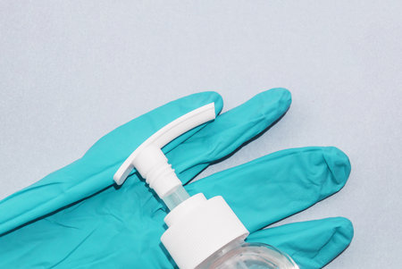 Top-down view sanitizer anti-sentic medical liquid and anti-coronavirus COVID-19 in plastic pump press head white transparent bottle on blue disposable gloveの写真素材