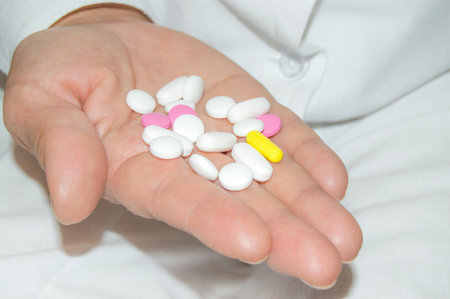 Open palm of a woman with a bunch of white and pink pills, health and medicine concept, close-upの写真素材