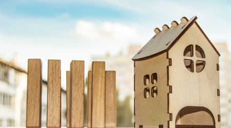 Real estate concept, home construction and mortgage, financial risks in real estate, transaction planning, wooden house and blocks against a blue sky backgroundの写真素材