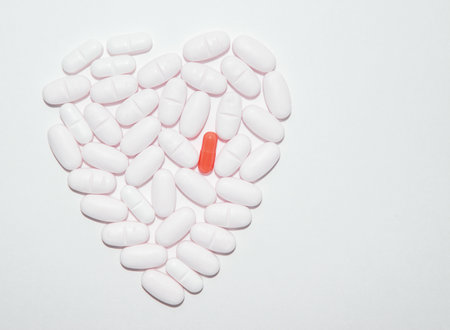 White pills of medication in the form of heart on a white background with one red pill, pharmaceutical concept, copy spaceの写真素材