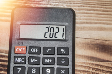 Black electronic calculator on dark wooden background, numbers show 2021の写真素材