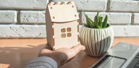 Home insurance concept, a woman holding a small wooden house on her hand, mortgage loan, home insurance, protection of family life, financial mortgage for building a houseの写真素材