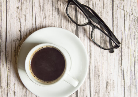 White espresso Cup and black stylish glasses on wooden background, top view, business concept pauseの写真素材