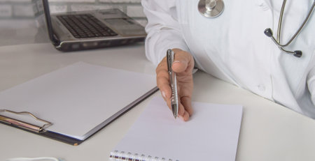A female doctor talks to a patient, explains the concept of treatment, against the background of a laptop in the medical officeの写真素材