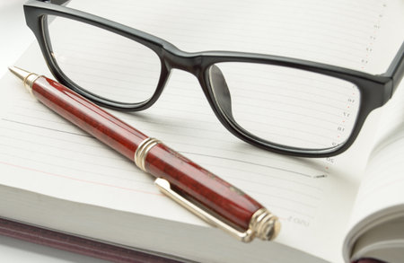 Luxury mens accessories - stylish black glasses and a pen on an open diary, close-upの写真素材