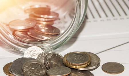 Close-up of Euro coins in a glass jar, scattered on the table, the concept of saving and investingの写真素材