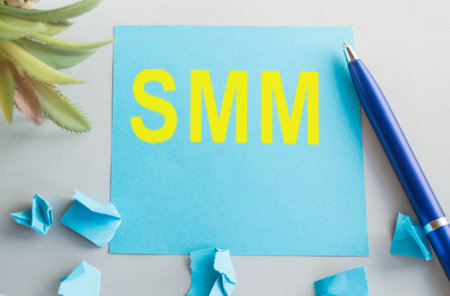 The word SMM is written in yellow letters on blue paper, next to a pen and crumpled sheets, a social media marketing conceptの写真素材