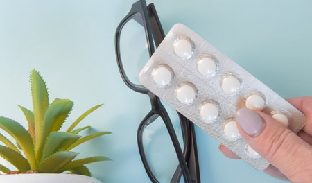 The hand holding the pill near the points, the concept of treatment of eye diseases and vision. Health. The concept of ophthalmologyの写真素材