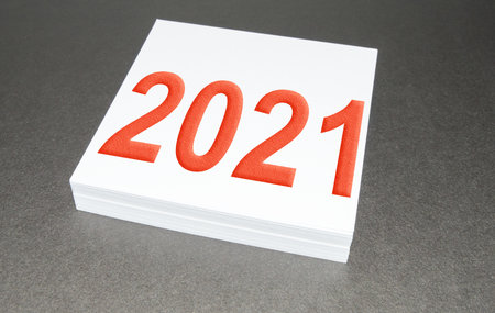 On a stack of square note paper is written 2021, the New years concept, on a black backgroundの写真素材