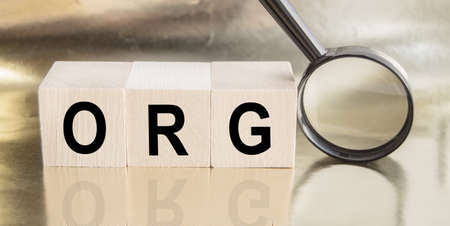 Wooden cubes with the word ORG concept. Magnifying glass with the word on a wooden table. Business concept. Finding an ideaの写真素材