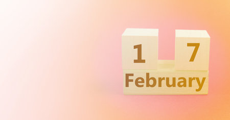 Wooden cube shaped calendar for February 17 on a gradient yellow pink background with a blank space for textの写真素材