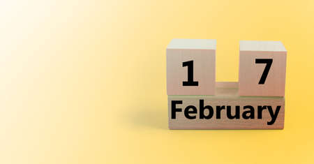 Wooden cube-shaped calendar for February 17 on a gradient yellow background with a blank space for textの写真素材