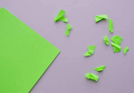 Corner green paper with a copy of the space on a gray background and small torn and crumpled pieces of paper, a template for your designの写真素材