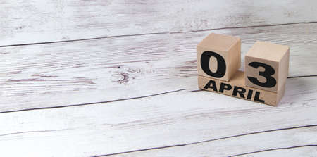 Vintage wooden calendar block real date 03 and the month of April on a light wooden table, copy the text space next to the April symbolの写真素材