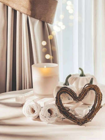 creative combination of rattan in the shape of love, white pumpkin, candle flame in a white glass against a white modern curtain background.の写真素材