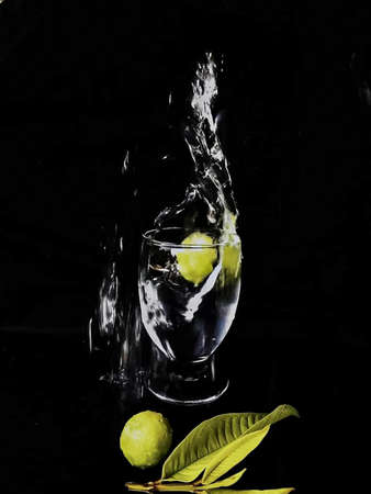 Lemon splashing into a glass of water on a black backgroundの写真素材