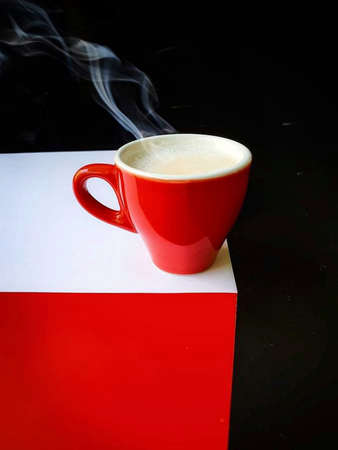Cup of coffee with smoke on a red and white background.の写真素材