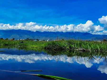 Reflection of blue sky and white clouds in the lake with grassの写真素材