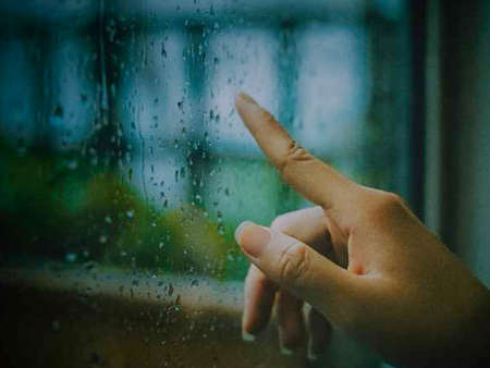 The hand of a man on the background of a wet window.