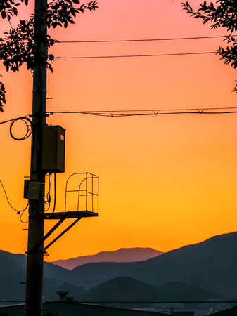 electric poles and moon on a beautiful orange sky background.の写真素材