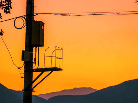 electric poles and moon on a beautiful orange sky background.の写真素材