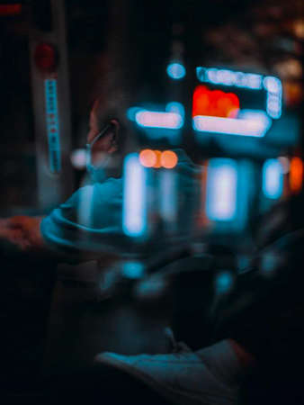 A man in a medical mask is sitting in the street at night.の写真素材