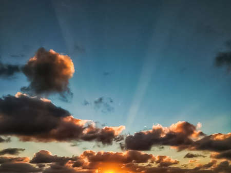 Sunset sky with clouds and sunbeams, natural background.の写真素材
