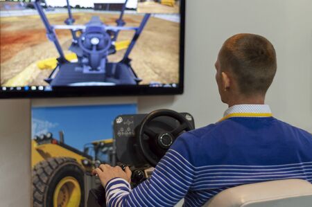 A man controls a tractor simulator - an excavator, rear view. Surgut, Russia - September 30, 2019.
