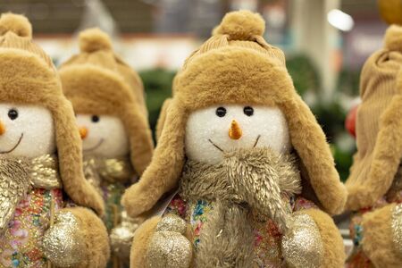Snowmen plush toys in beige hats and fur coats are in two rows and are waiting for when they are bought for new year 2020. Front view.の写真素材