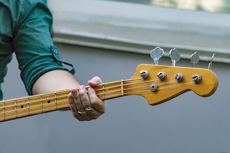 Man in light shirt plays bass guitar. Front view.