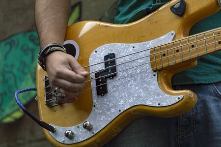 Man in light shirt plays bass guitar. Front view.