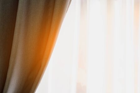 Fragment of assembled curtains and glare of sun from window. Front view of room.の写真素材