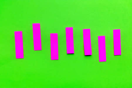 Purple pink vertical paper stickers on bright green paper. Horizontal shot. Front view.