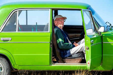 Old man with glasses in the car. In the passenger seat. The door is open.の写真素材