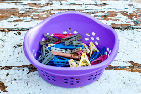 Colored clothespins for linen in container. Round box purple on the blue surface, view from the top...