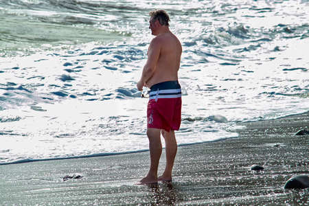 Man stands on beach near water. A sunny autumn day is a side view. Sudak, Crimea - 10 October 2020.のeditorial素材