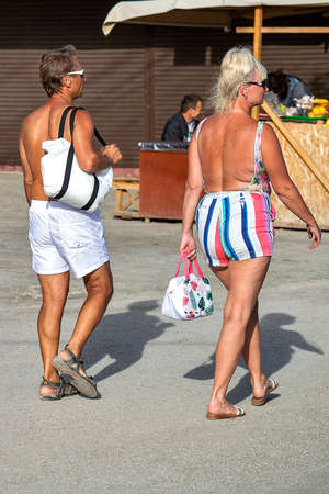 Man and woman walk along sea promenade. A sunny autumn day is back view. Sudak, Crimea - 10 October 2020.のeditorial素材