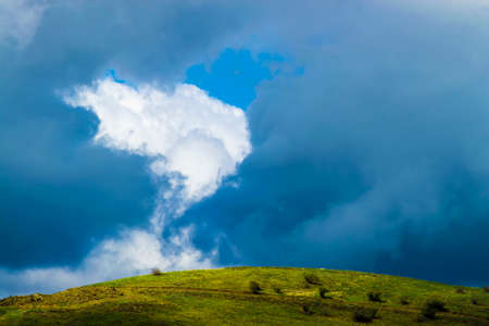 Green hill and gray clouds. Front view on a rainy autumn day.