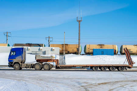 Truck with long platform to transport other transport driving on road. Surgut, Russia - 10 March, 2021.のeditorial素材