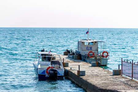The sea boats moored to the pier. Sunny summer day. Front view. Crimea, Sudak - 10 October 2020.のeditorial素材