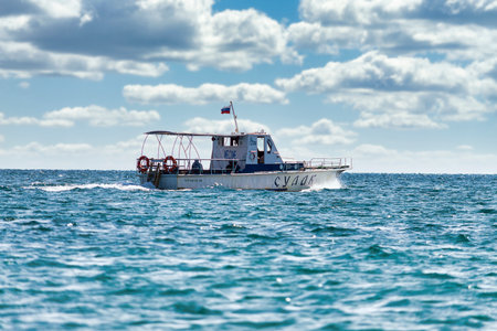 White fast boat sails by sea. Sunny autumn day. Side view. Crimea, Sudak - 10 October 2020.
